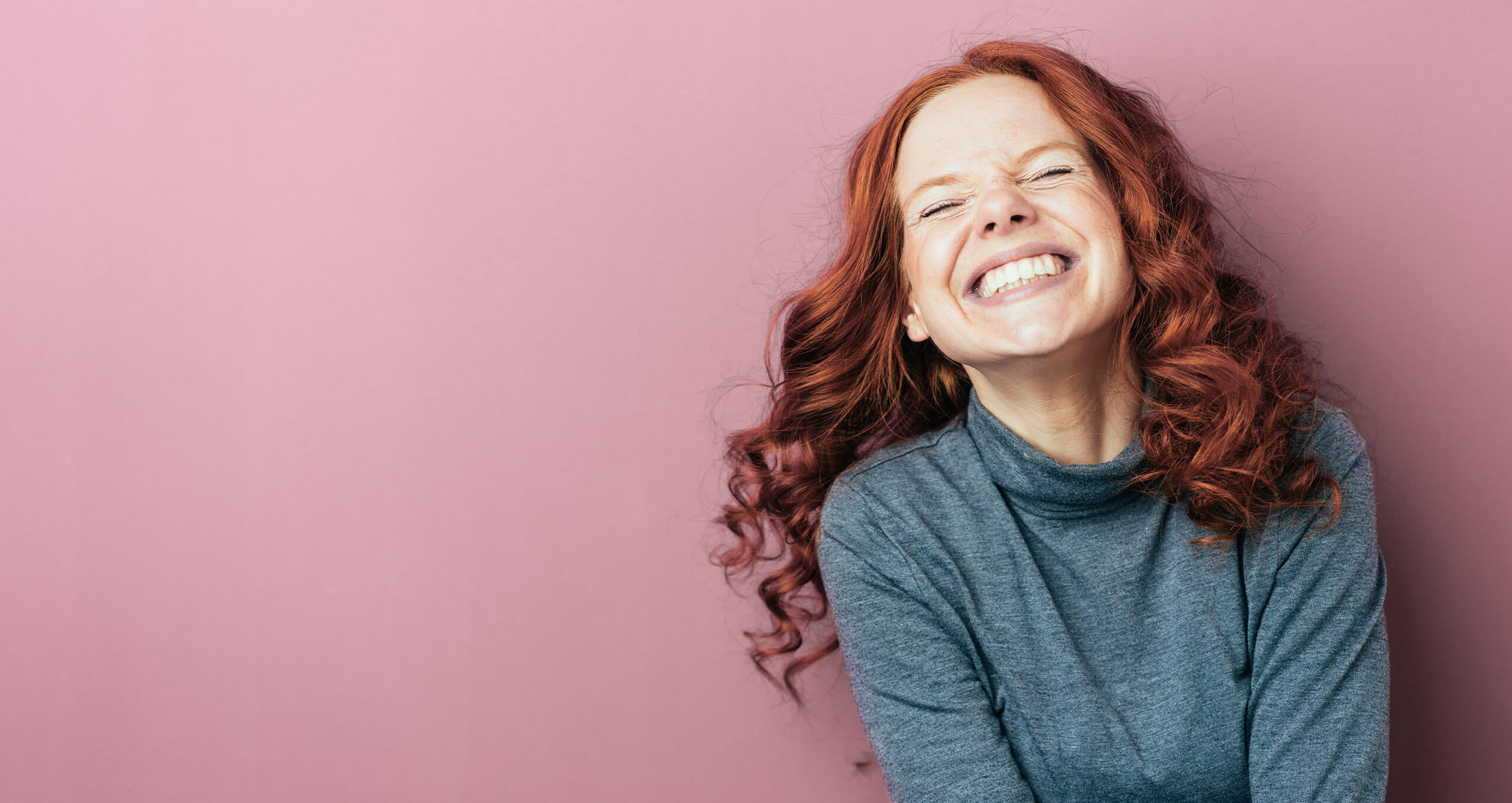 Girl smiling widely against a pink background | Loughborough Orthodontic and Implant Clinic